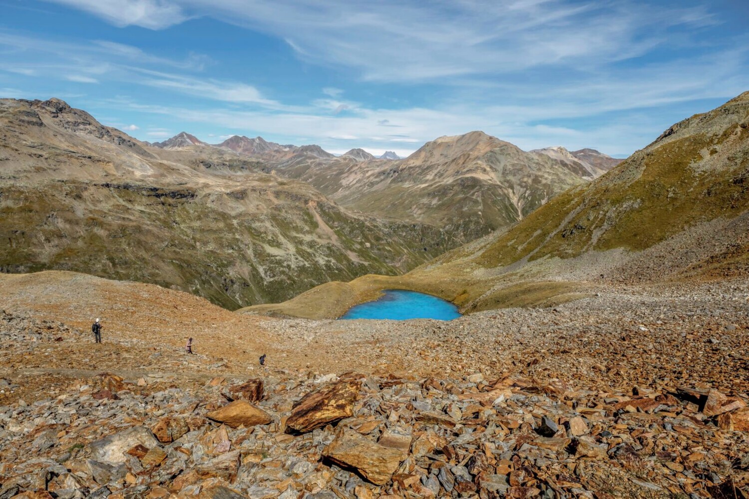 Rotes Pyritgestein, türkisblauer See, grüne Berghänge.
