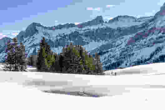 Kleiner Schneeschuhwanderer vor grossen, schattigen Felswänden. Bild: Fredy Joss