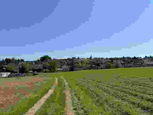 Un chemin de campagne traverse la plaine agricole de la Reuss. En arrière-plan, Hünenberg