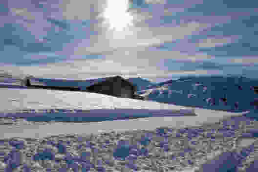 Tief verschneit sind die Alphütten im Winter. Langläufer und Winterwanderer ziehen vorbei.